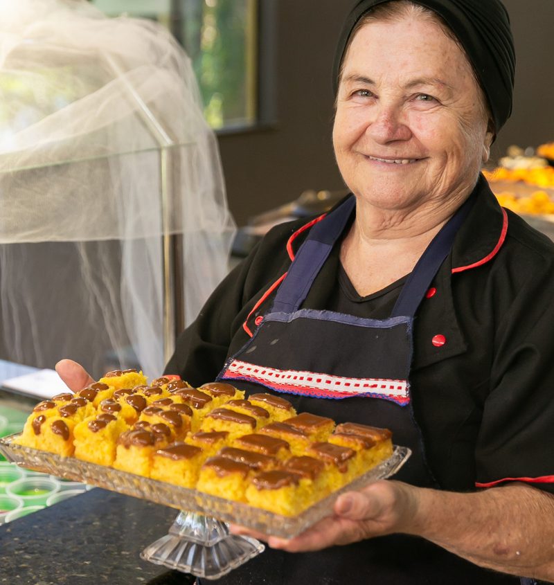 Cozinheira sorrindo com tabuleiro de doces